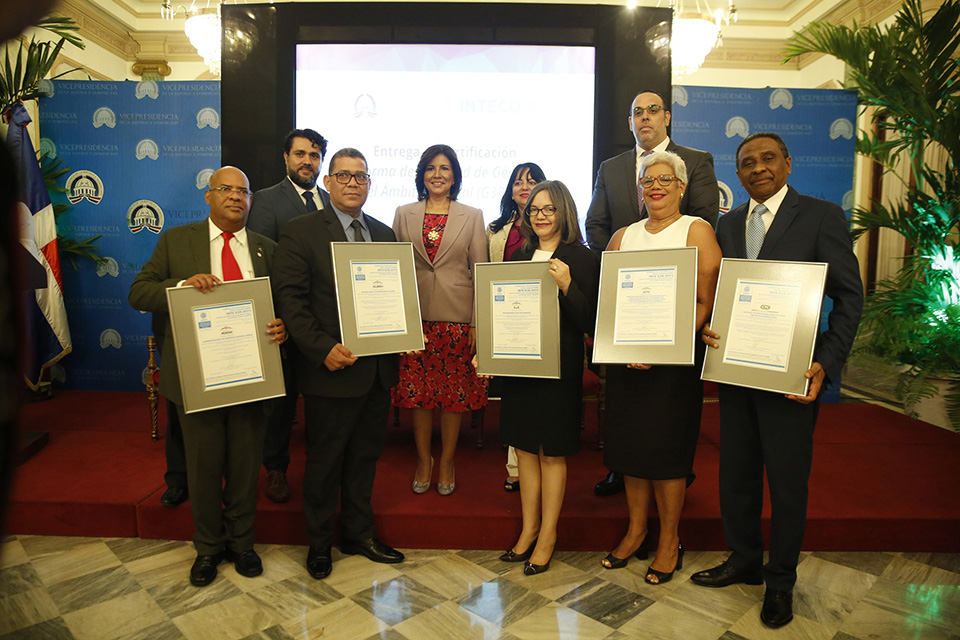 La vicepresidenta de la República, doctora Margarita Cedeño, junto a (derecha) Jonathan Pérez, director de Servicios de Evaluación del Instituto de Normas Técnicas de Costa Rica (INTECO); Héctor Medina, director del Sistema Único de Beneficiarios (Siuben); y Ramón González, director de la Administradora de Subsidios Sociales (Adess); (izquierda) Nereida Rodríguez, directora interinstitucional de Recursos Humanos de la Vicepresidencia, Gerardo Tejera, director país de INTECO; Altagracia Suriel, directora de Progresando con Solidaridad (Prosoli); Rosa María Suárez, directora técnica del Gabinete de Coordinación de Políticas Sociales (GCPS), y Claudio Doñé, director de Centros Tecnológicos Comunitarios (CTC), quienes sostiene la certificación de la Norma de Igualdad de Género en el Ámbito Laboral (G38:2015).